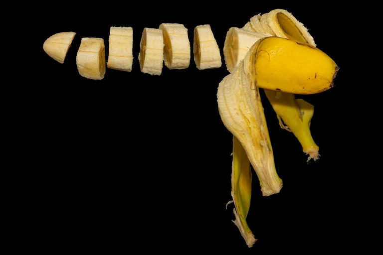 Schwebende Banane, zerschnitten, vor schwarzem Hintergrund